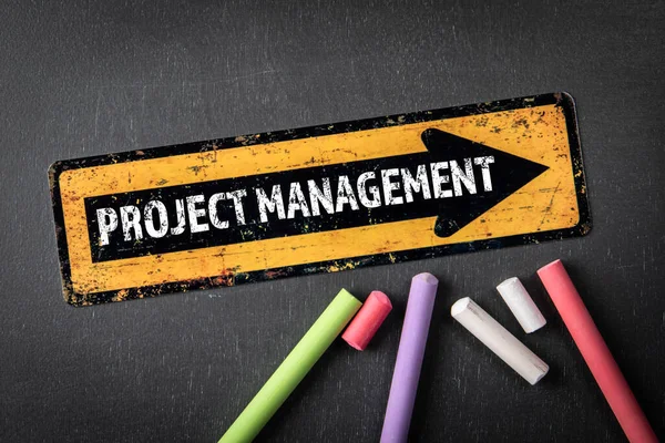 Project management. Yellow directional arrow with text on a dark chalkboard background.
