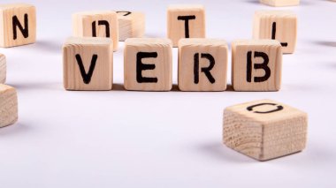 VERB. Beyaz arkaplanda tahta alfabe blokları.