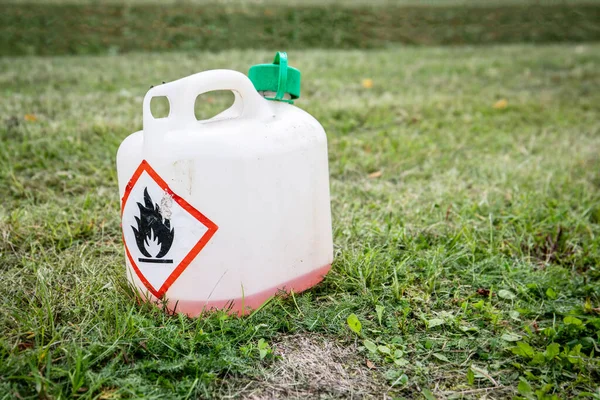 Plastic can in cut grass. Fire danger sign.