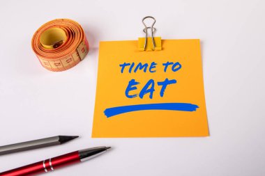 Yemek zamanı. Beyaz arkaplan üzerinde metin olan sarı not defteri.