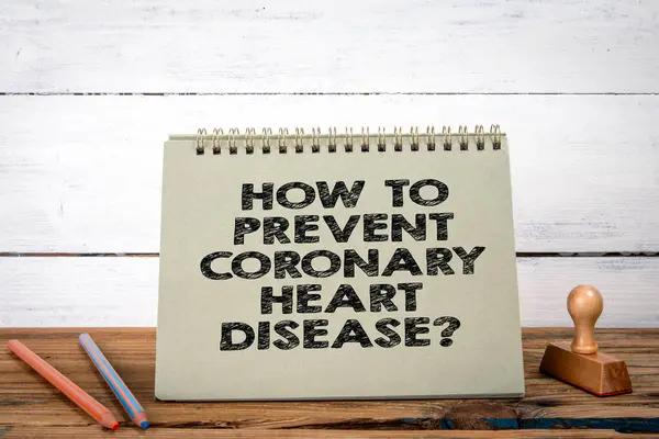 How to Prevent Coronary Heart Disease. Green notepad on wooden texture table and white background.