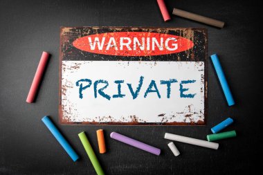 Özelleştir. Kara karatahta arka planında metal uyarı işareti ve renkli tebeşir parçaları.