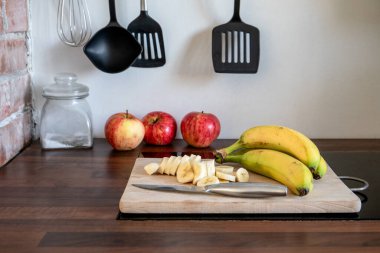 Modern bir mutfakta tahta bir tahtanın üzerinde dilimlenmiş muz..