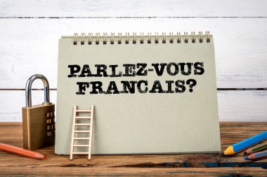 Fransızca konuşabiliyor musun? Fransızca yazılmıştı. Ahşap doku tablosunda yeşil not defteri ve beyaz arkaplan.
