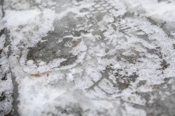 Frozen water on the sidewalk, footprints in the ice. Weather conditions and climate.