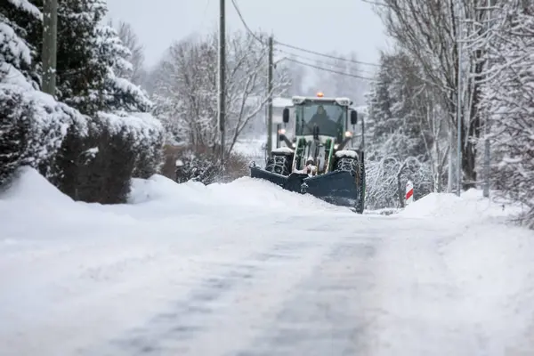 Tractor clears snow on road after heavy snowfall, road maintenance in winter season, harsh weather.