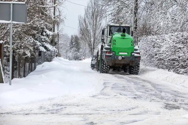 Tractor clears snow on road after heavy snowfall, road maintenance in winter season.
