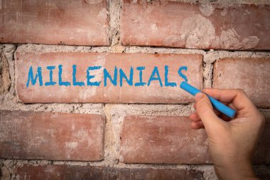 Millennials. Text written with purple chalk on a red brick background. clipart