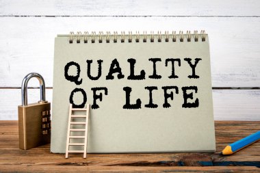 Yaşam kalitesi. Ahşap doku tablosunda yeşil not defteri ve beyaz arkaplan.