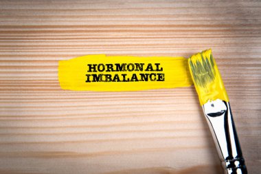 Hormonal dengesizlik. Ahşap arkaplanda sarı boya ve boya fırçası.