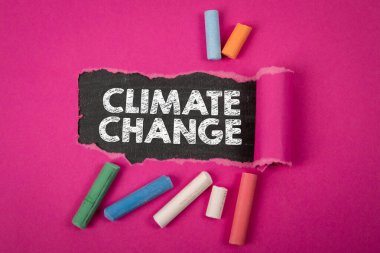 İklim değişikliği. Tahtadaki yırtık mor kağıdın altında metin.