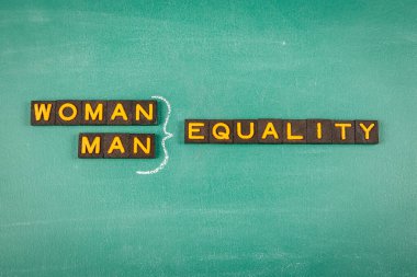 Woman Man Equality Concept. Old letter tiles on a green chalkboard background. clipart