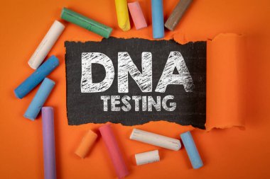 DNA testi. Tahtada yırtık turuncu kağıdın altında metin.