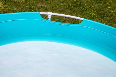 Su dolu çimlerin üzerinde mavi çocuklar havuzu var..