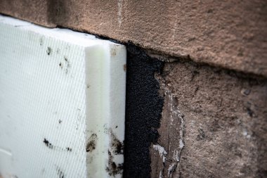 Temellerdeki köpük panoların ve katranın yakın plan çekimi, enerji verimliliğini artırır.