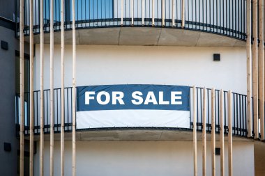 Bir apartmanın önünde satılık tabelası var..