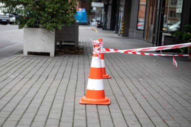İki turuncu ve beyaz uyarı konisi ve kaldırımda çizim bandı..