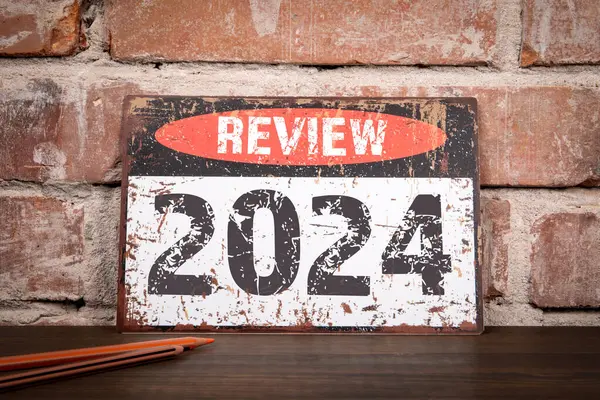 2024 Konseptini gözden geçir. Ahşap dokuma ofis masasında yazılı metal tabela..