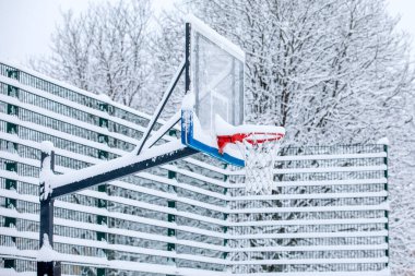 Kışın bahçede karla kaplı basketbol potası..
