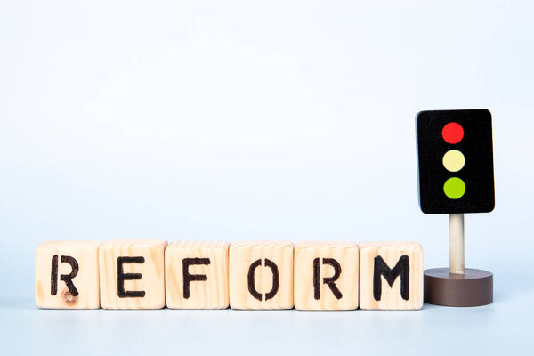 REFORM Concept. Miniature traffic light on a light background.