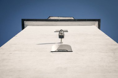 Low-Angle View of a Minimalist White Building with Vintage Lamp Against a Clear Blue Sky. clipart