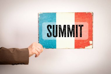 Zirve İşareti. Hafif arka planda bayrak sallayan bir kadın..