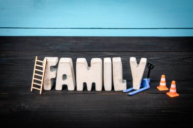 - Aile. Mavi ve siyah ahşap arka planda somut alfabe harfleri.