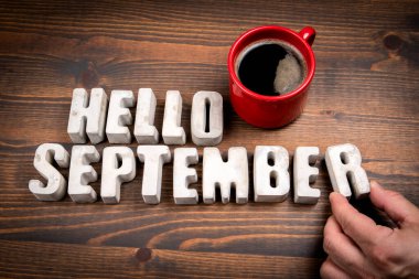 Merhaba Eylül. Somut alfabe harfleri ve koyu ahşap arkaplanda kahve fincanı..