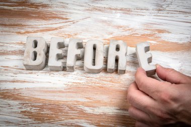 Öncesinde. Hafif boyalı ahşap arkaplanda somut alfabe harfleri.