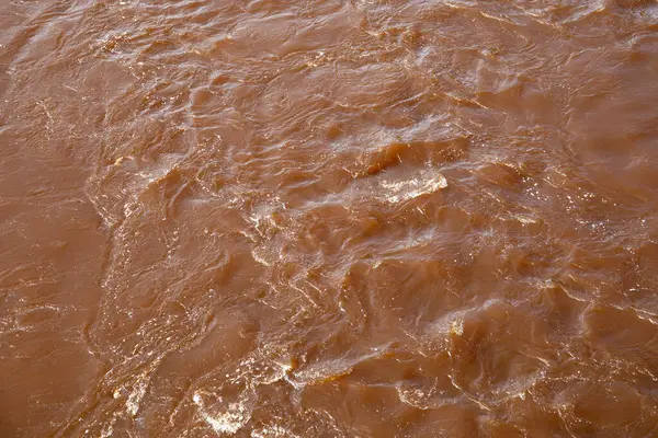 Doğal Gün Işığında Yansıma ve Akış Şablonlarıyla Çalkantılı Kahverengi Nehir Suyu.