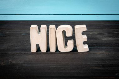 Tahta zemin ve mavi zemin üzerine beton harflerle hoş bir kelime..