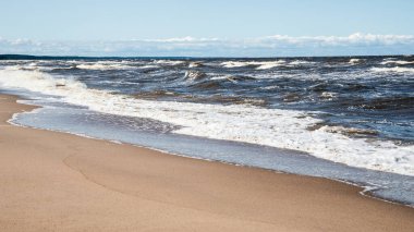 Dalgalar Kum Sahili kıyısına çarpıyor Parlak Mavi Yaz Gökyüzünün altında.