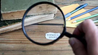 Bugün sizin kavramınız. Ahşap desenli bir ofis masasında büyüteç. 4K Video