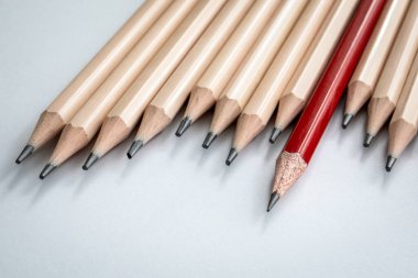 Kırmızı Kalem Beyaz Arkaplanda Üniformalı Bej Kalemlerin Arasında Duruyor.