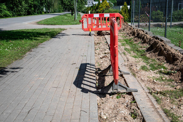 Sidewalk Construction Zone with Red Barrier Blocking Pedestrian Access on a Sunny Day.
