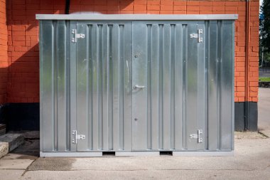 Çelik Kapı ve Turuncu Tuğla Duvarlı Endüstriyel Metal Depolama Birimi.