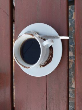 Beyaz fincanda sade kahve. Masanın üstü görünüyor. Günün tadını çıkarmak için kafe içkisi menüsü konsepti. Kahve lekeli fincan.