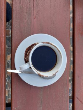 Beyaz fincanda sade kahve. Masanın üstü görünüyor. Günün tadını çıkarmak için kafe içkisi menüsü konsepti. Kahve lekeli fincan.