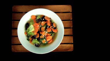 Siyah arka planda kızartılmış mantar ve havuç. Besleyici sağlıklı yemek menüsü beyaz bir kasede servis edilir. Sağlıklı sebze yemeği kavramı. Çeşitli yemek ihtiyaçları için.