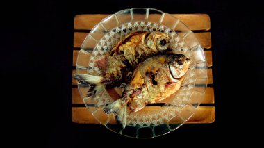 Tatlı su pomfret. Tabak ve tabakta servis edilmiş. Kızarmış balık menüsü. İzole edilmiş siyah arka plan. Gıda dergisi katalogları ve doğal sağlıklı yiyecek kavramları için iyidir.