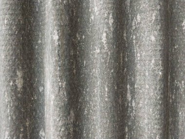 Asbest çatısını kapatın. Gri desenli ve dalgalı çatı. Ev çatısı konsepti ya da çatı seçiminin sağlık teması. Çatı arkaplanı. Gri asbest çatı