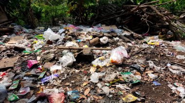 Çürümemiş çöp yığınları. Plastik çöpler bahçeyi dolduruyor. Çevre kirliliği kavramı. Çöpün arka planı