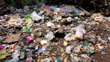 Çürümemiş çöp yığınları. Plastik çöpler bahçeyi dolduruyor. Çevre kirliliği kavramı. Çöpün arka planı