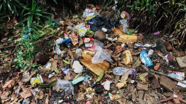 Çürümemiş çöp yığınları. Plastik çöpler bahçeyi dolduruyor. Çevre kirliliği kavramı. Çöpün arka planı