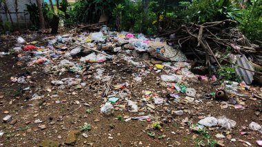 Çürümemiş çöp yığınları. Plastik çöpler bahçeyi dolduruyor. Çevre kirliliği kavramı. Çöpün arka planı