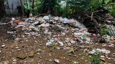 Çürümemiş çöp yığınları. Plastik çöpler bahçeyi dolduruyor. Çevre kirliliği kavramı. Çöpün arka planı