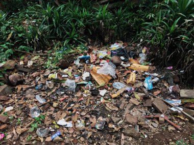 Çürümemiş çöp yığınları. Plastik çöpler bahçeyi dolduruyor. Çevre kirliliği kavramı. Çöpün arka planı