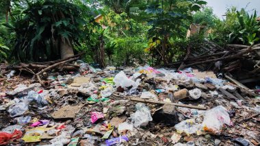 Çürümemiş çöp yığınları. Plastik çöpler bahçeyi dolduruyor. Çevre kirliliği kavramı. Çöpün arka planı