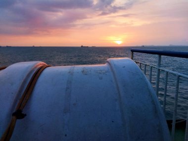 Teknedeki ufuk manzarası. Gün batımı. Deniz ve gökyüzünün güzelliğinin arkaplanı turuncuya dönmeye başlıyor. Güneş batıyor, gökyüzü renklerle dolu..