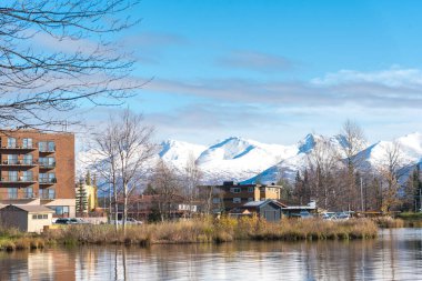 Lakeside apartmanı ve Anchorage, Alaska 'daki Chugach Dağı' nda kar örtüsü olan Spenard Gölü 'ndeki deniz uçağı üssü yakınlarındaki yazlık. Sonbaharın başlarında ağaçlarla dolu uçaklar yüzer.